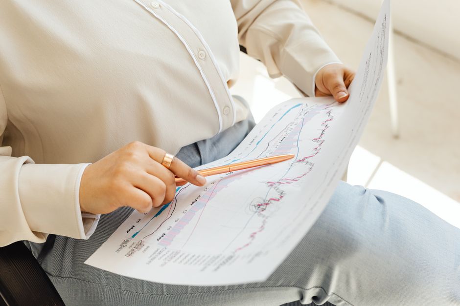 Trading calls and puts — Close-up of hands holding and analyzing finance charts with pen.